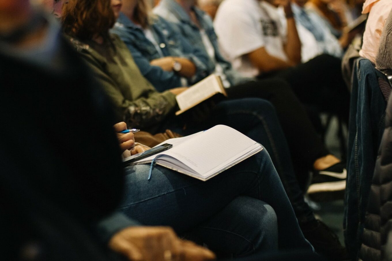 individuals sitting in a pew with bibles open on lap