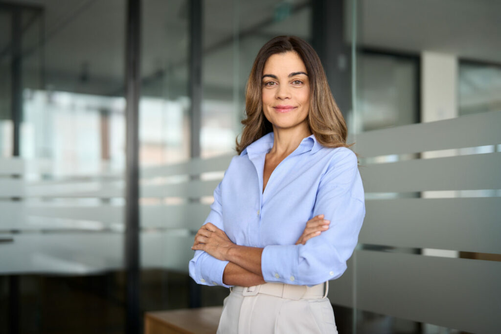 woman in business attire standing confidentially with arms crossed