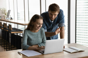 hr manager and subordinate discussing hr related systems around a laptop