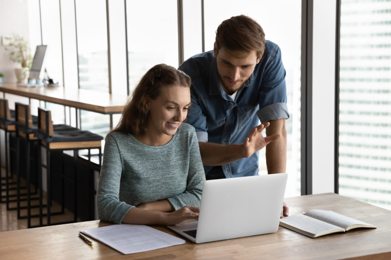hr manager and subordinate discussing hr related systems around a laptop