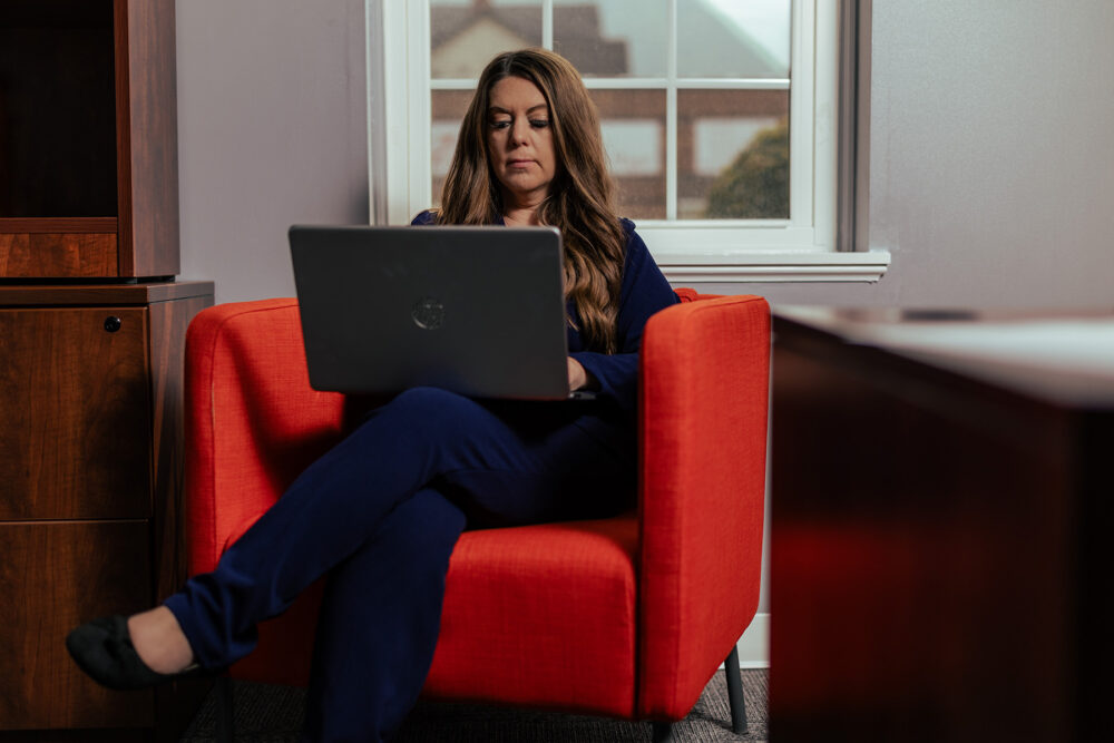 a busy hr leader sitting in a chair working diligently on a laptop