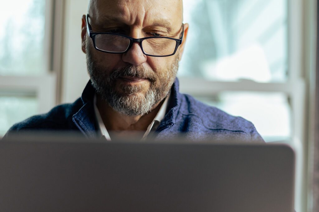 man with glasses working on laptop