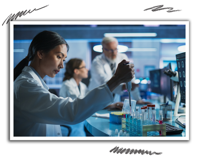 a scientist carefully working with test tubes as coworkers discuss topics in the background