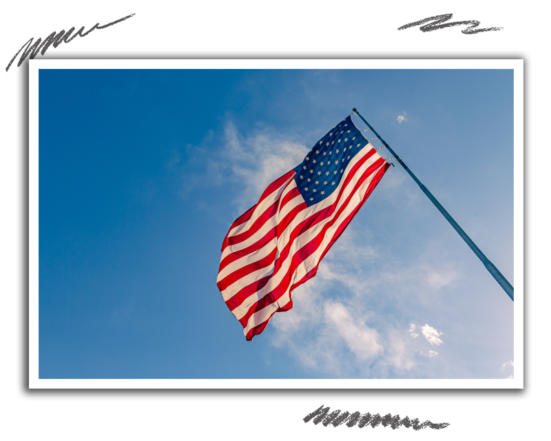 the american flag flapping in the wind against a party cloudy blue sky