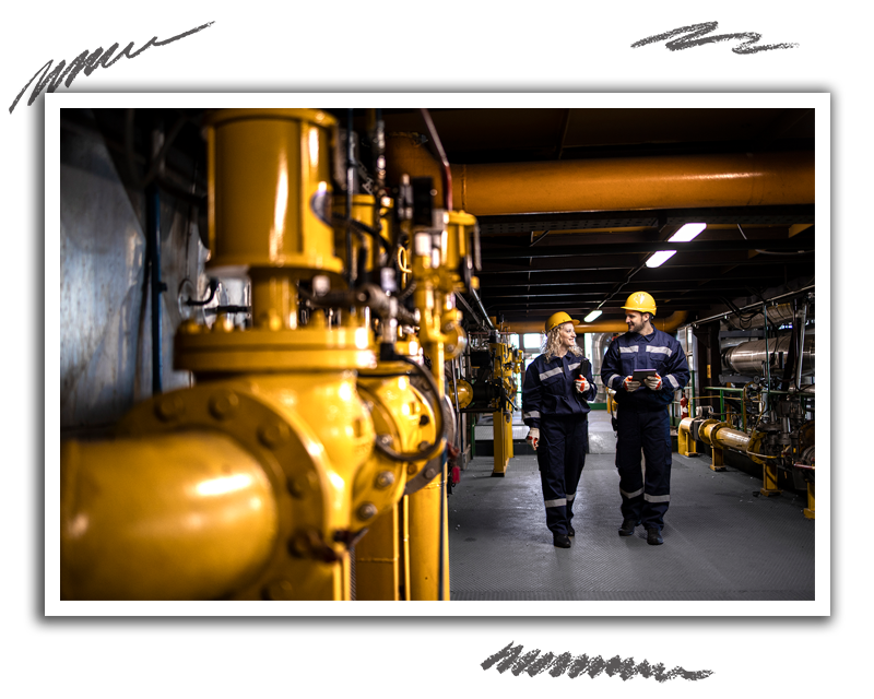 two oil and gas workers discussing plans while walking alongside pipe