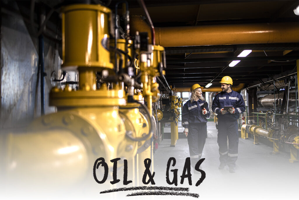 two oil and gas workers discussing plans while walking alongside pipe