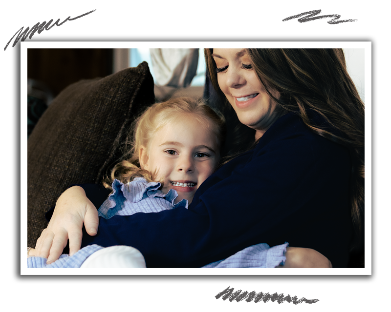 a young girl smiling as she is wrapped up in an embrace by a woman