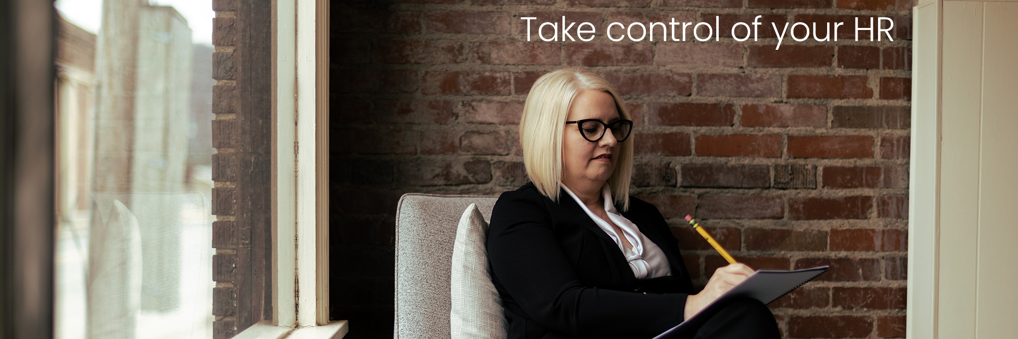 hr leader sitting on a relaxed chair against a brick background working on a report